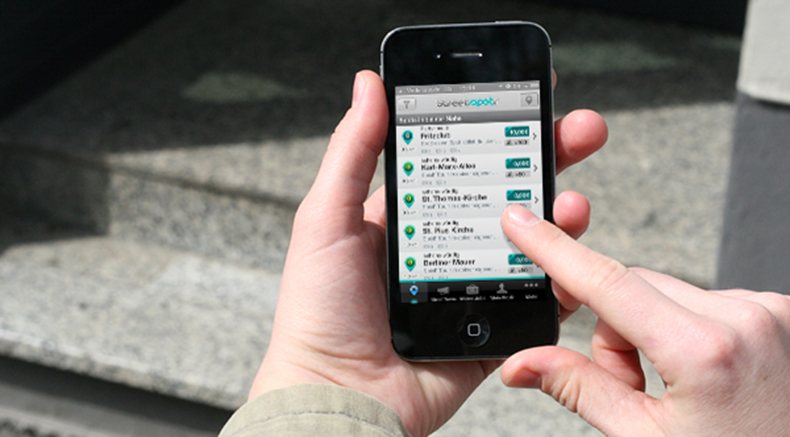 Foto von einem Smartphone, welches gerade von einer Person bedient wird. Die App "Streetspotr" ist geöffnen.