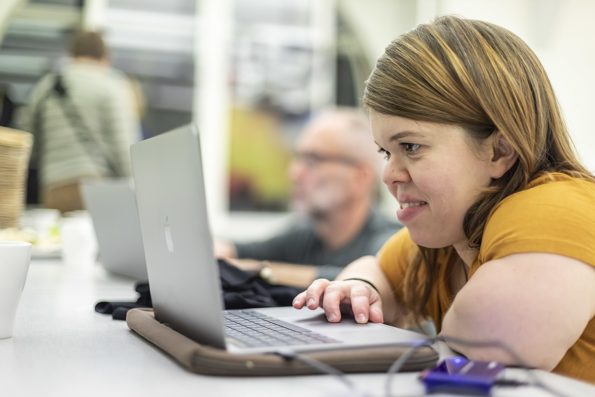 Foto von Teilnehmerin Workshop sitzt an Laptop, arbeitet, lächelt