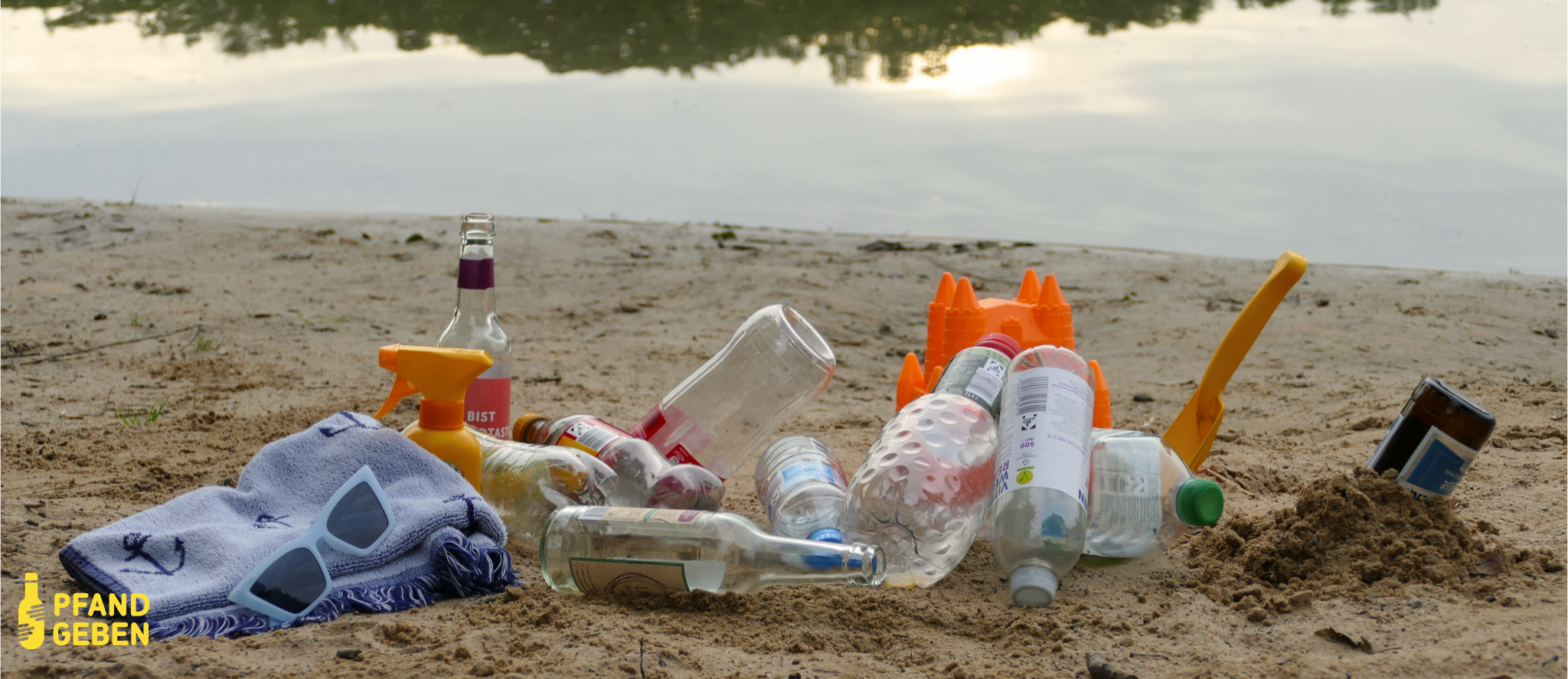 Foto von einem See mit Sandstrand beim Sonnenuntergang. Im Sand liegen verschiedene leere Pfandflaschen, ein Handtuch und eine Sonnenbrille.