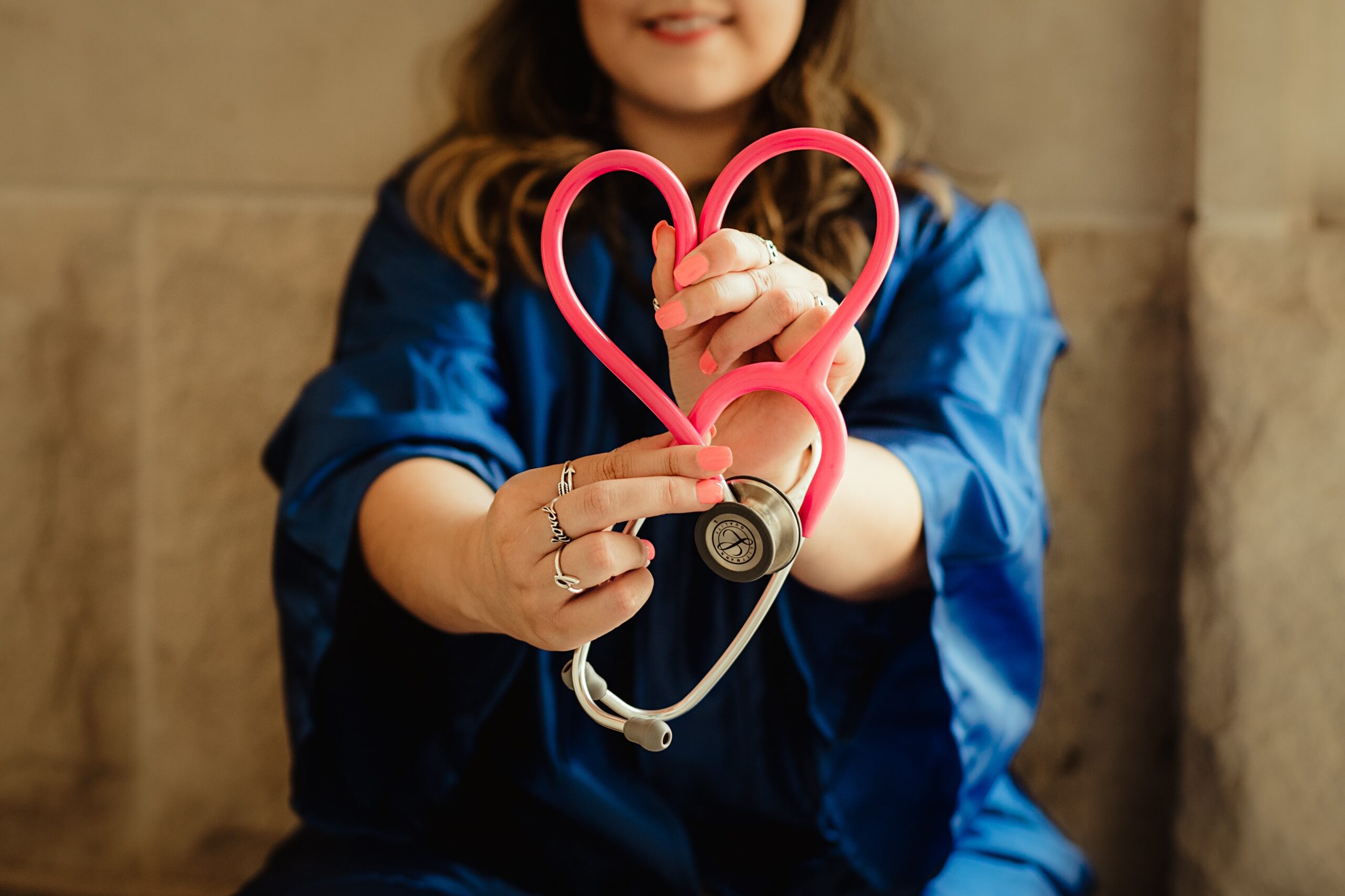 Foto von einer Person, die ein Stethoskop hält und daraus ein Herz formt.